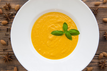 Creamy pumpkin soup with basil leaves and spices, top view. Traditional american autumn dish. 