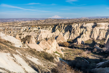 Fototapeta na wymiar Aerial view of various rocks and Cave hotel in the valley of Goreme against blue sky, built in rock formation in national park Goreme,Cappadocia ,Turkey.