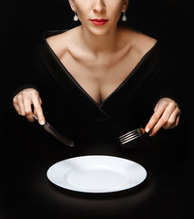 knife and fork in woman's hands over white plate