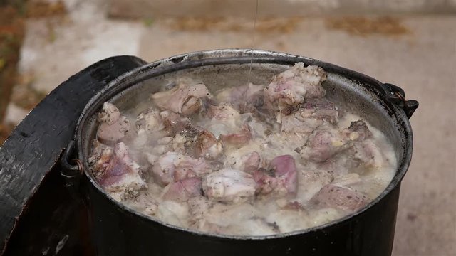 Farmer cooking pastirma or lamb jerky, outdoor in a cauldron