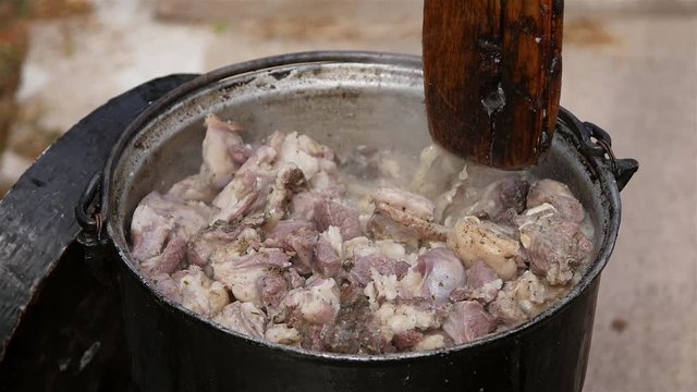 Farmer cooking pastirma or lamb jerky, outdoor in a cauldron