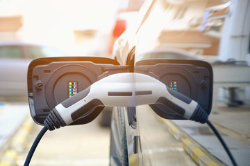 Charging modern electric car battery on the street which are the future of the Automobile, Close up of power supply plugged into an electric car being charged for hybrid . New era of vehicle fuel.