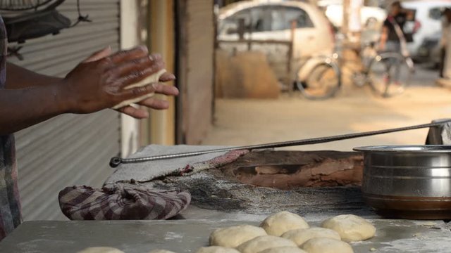 A man putting handmade chapati/ roti/naan bread in Tandoor, a cylindrical clay or metal oven used in cooking and baking in Northern India. It's used for cooking in Southern, Central and Western Asia
