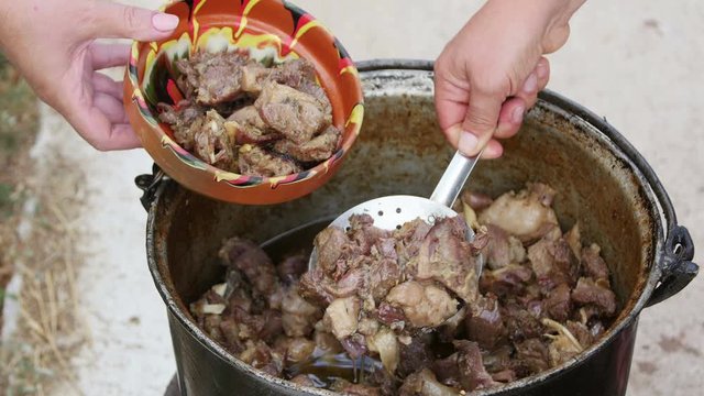 Farmer cooking pastirma or lamb jerky, outdoor in a cauldron