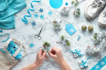 Wintertime, creative flat lay with various winter craft supplies, christmas tree twigs and hands decorating gift boxes