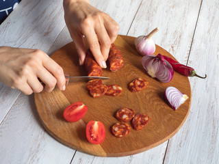 Chorizo sausage is sliced on a wooden chopping board.