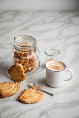 Italienische Blätterteig Fächer Kekse mit Einmachglas und Becher Kaffee auf Marmor Hintergrund