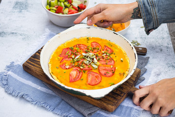 Hands holds pumpkin veggie casserole  with tomatoes and herbs. Vegan food and vegetarian lunch.