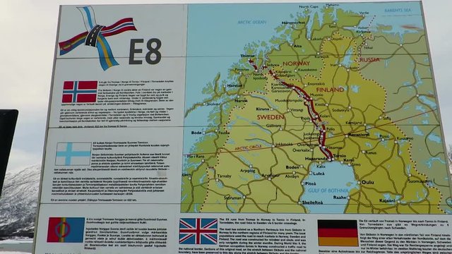 Billboard map on the road snowing the E8 route in Scandinavia with descriptions in five different languages.