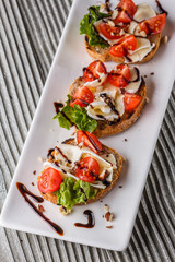 Bruschetta with tomatoes, lettuce, camambert, balsamic vinegar