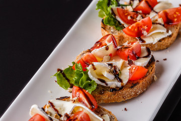 Bruschetta with tomatoes, lettuce, camambert, balsamic vinegar