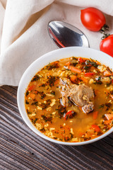 Georgian soup. Kharcho with rice, tomato, beef, garlic and herbs in bowl on wooden table