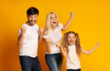 Excited Parents And Daughter Shaking Fists Celebrating Success In Studio