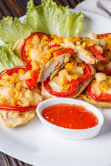 Chicken fillet in a batter with corn, paprika, lettuce and spicy tomato sauce on white plate