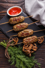 Shish kebab on the skewers with sauce, grilled mushrooms on rustic table