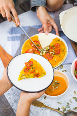 Hands holds pumpkin veggie casserole  with tomatoes and herbs. Vegan food and vegetarian lunch.