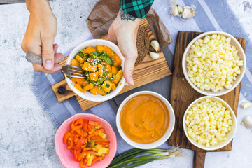 Woman hands holds yellow tomatoes salad. Pumpkin puree, red bell pepper salad on table. Vegan food, vegetarian lunch.