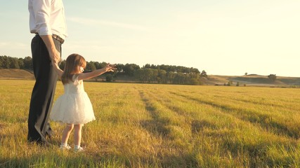 Dad and Mom teach daughter to ride bike. Mother and father play with small child on lawn. kid learns to ride bicycle. parents and little daughter walks in park. concept of happy family and childhood