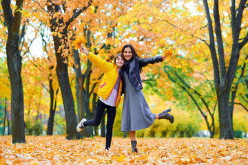 woman having fun with autumn leaves in city park, outdoor portrait