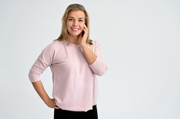 Close-up portrait of a cute caucasian blonde female student girl in pink blouse on a white background. Wide smile, happiness. It is in different poses.
