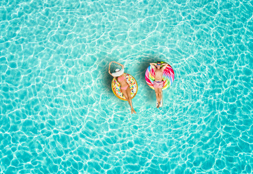 Junges Paar genie&szlig;t den Urlaub auf bunten Luftmatratzen &uuml;ber t&uuml;rkisem, tropischen Meer der Malediven