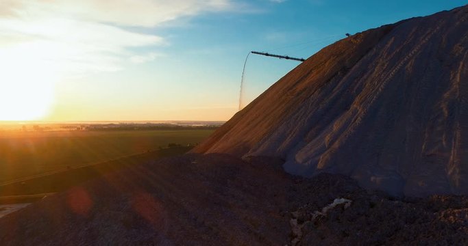 Mountains tailing piles and water basins. Waste left after potash salt ore extraction from underground mines falling from the conveyor belt. Environmental pollution from industrial production.