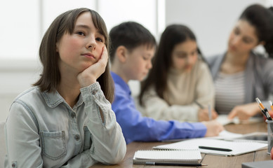 Bored girl sitting at lesson in classroom
