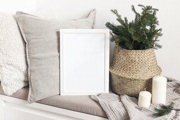 White blank wooden frame mockup with Christmas tree, candles, linen cushions and plaid on the white...