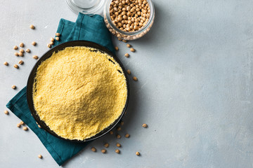 Chickpea flour in black ceramic bowl on light background top view with copy space