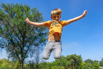 Joyful and happy boy is jumping up on the road.