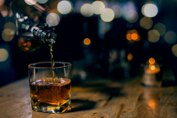 glass of whiskey and ice on wooden table - obrazy, fototapety, plakaty