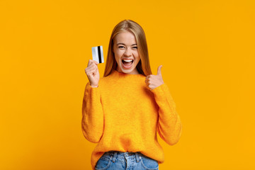 Carefree young girl showing thumb up, excited about upcoming shopping