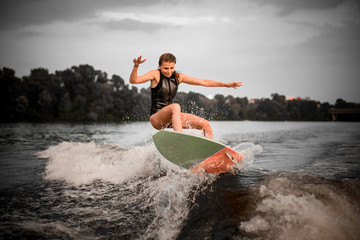 Sporty woman wakesurifing in the river near forest