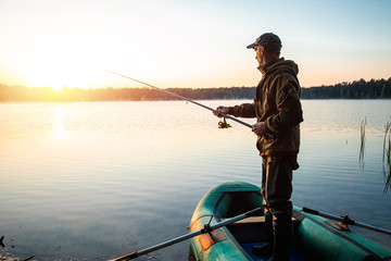 Male fisherman at dawn on the lake catches a fishing rod. Fishing hobby vacation concept. Copy...
