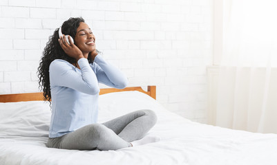 Cheerful young girl listening to music in bedroom