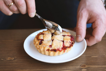 man in grey sweater drinks black lungo americano coffee in winter autumn in coffee shop eating classic american home-made cherry pie on white plate on wooden table. Fall mood instagram style