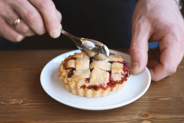man in grey sweater drinks black lungo americano coffee in winter autumn in coffee shop eating classic american home-made cherry pie on white plate on wooden table. Fall mood instagram style