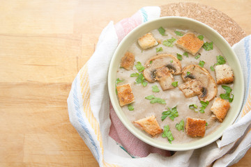 Cream of champignons soup with parsley and croutons, on a wooden background. Hot dish. Top view, food.