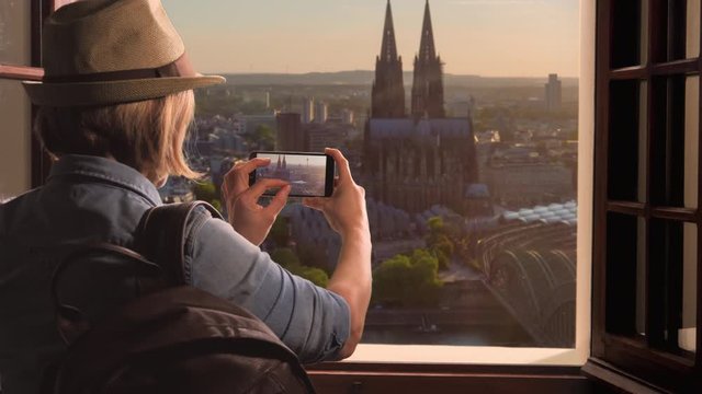 tourist takes picture of cologne city skyline and cathedral from a window