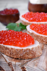 Sandwiches with bran bread, red caviar and butter on white wooden table