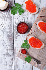 Sandwiches with bran bread, red caviar and butter on white wooden table. Top view