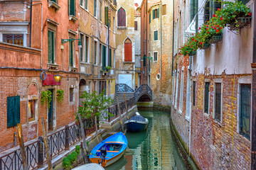 Narrow canal with boat and bridge in Venice, Italy. Architecture and landmark of Venice. Cozy cityscape of Venice.