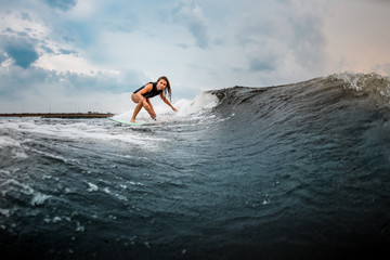 Young girl gliding on a wakeboard in the river near forest