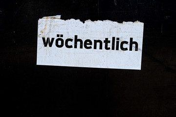 the word "wöchentlich" written in German language on a white sign on black background,  translated "weekly"
