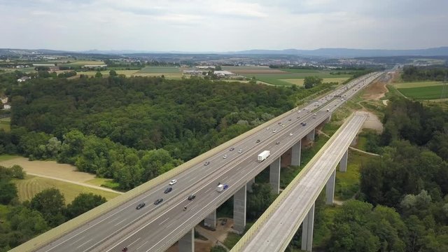Aerial view of a German Autobahn with construction works for a new railway bridge next to it. Drone footage taken at Denkendorf near Stuttgart - on a weekend, hence not much truck traffic.