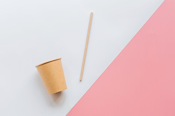 eco natural paper coffee cup and straw flat lay on white and pink background. sustainable lifestyle concept. zero waste, plastic free items. stop plastic pollution. Top view, overhead, mockup template