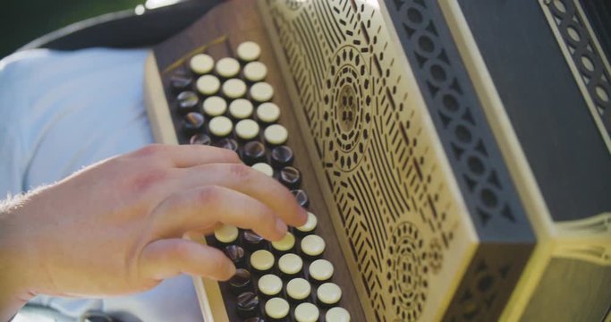 Close up slow motion shot man playing on accordion, musician hands.