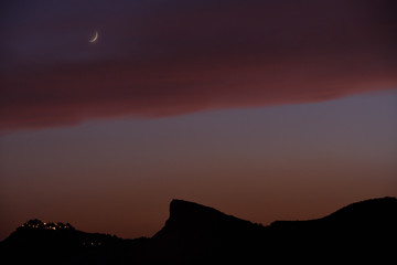 the peak of the mountain seems to point to a beautiful moon