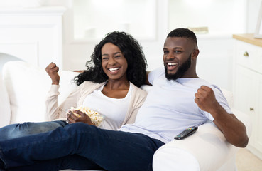 Married couple watching sport on tv, supporting their favorite team