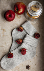 Grey knitted cozy socks on the windowsill, with cookies and apple with species. A cozy home atmosphere.